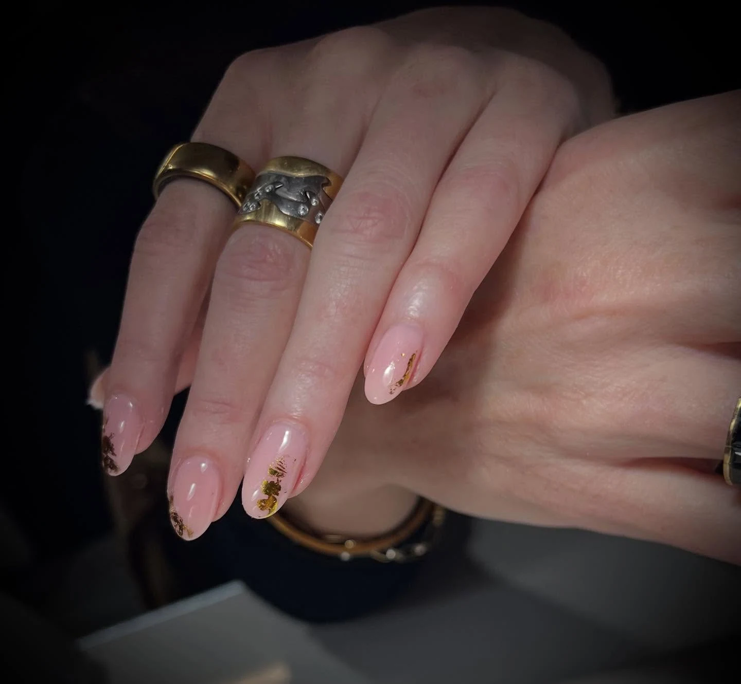 Sheer nude almond nails with gold-leaf flecks and botanical accents