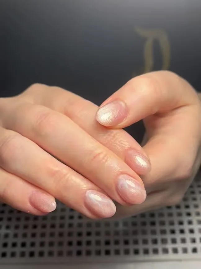 Pearlescent milky iridescent natural short round nails with faint gold cursive mark behind