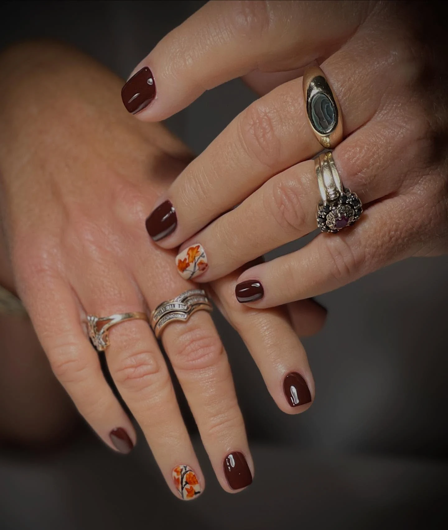 Deep burgundy nails with painted autumn-leaf accent