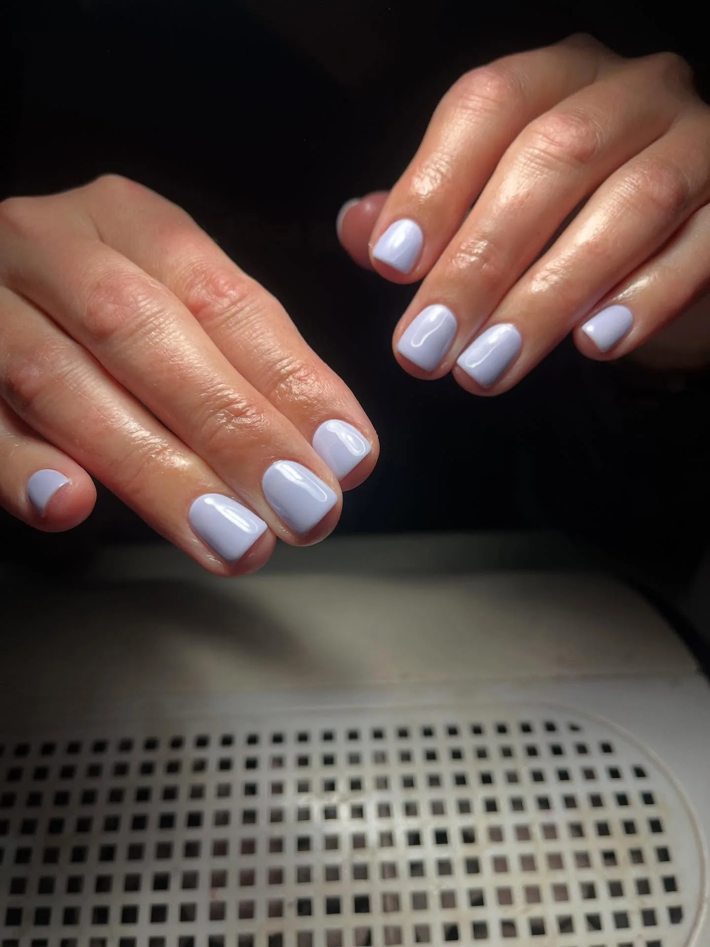 Pale lilac glossy short squoval nails over white LED lamp