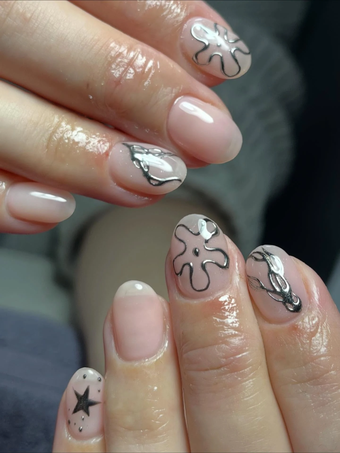 Sheer nude nails with silver-and-black chrome line-art and star accent