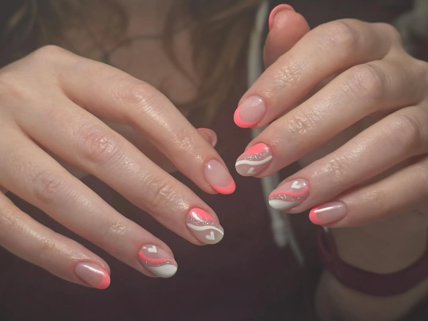 Neon-coral French tips with white swirl and tiny white heart accents