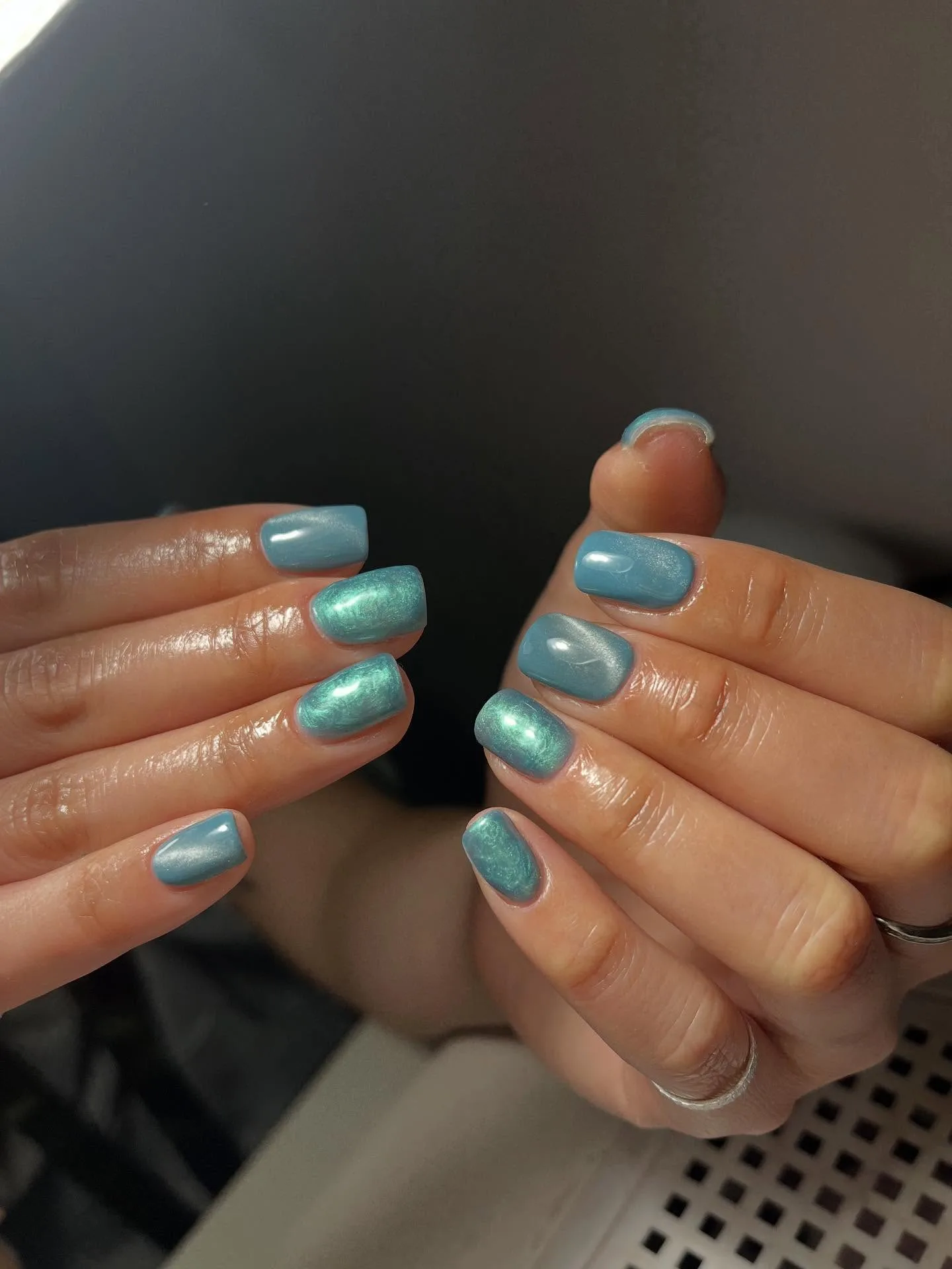 Teal pearl-shimmer squoval nails on dark background