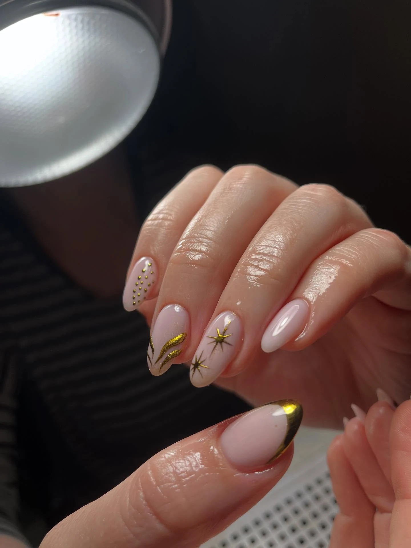 Soft nude almond nails with gold-star and starburst accents
