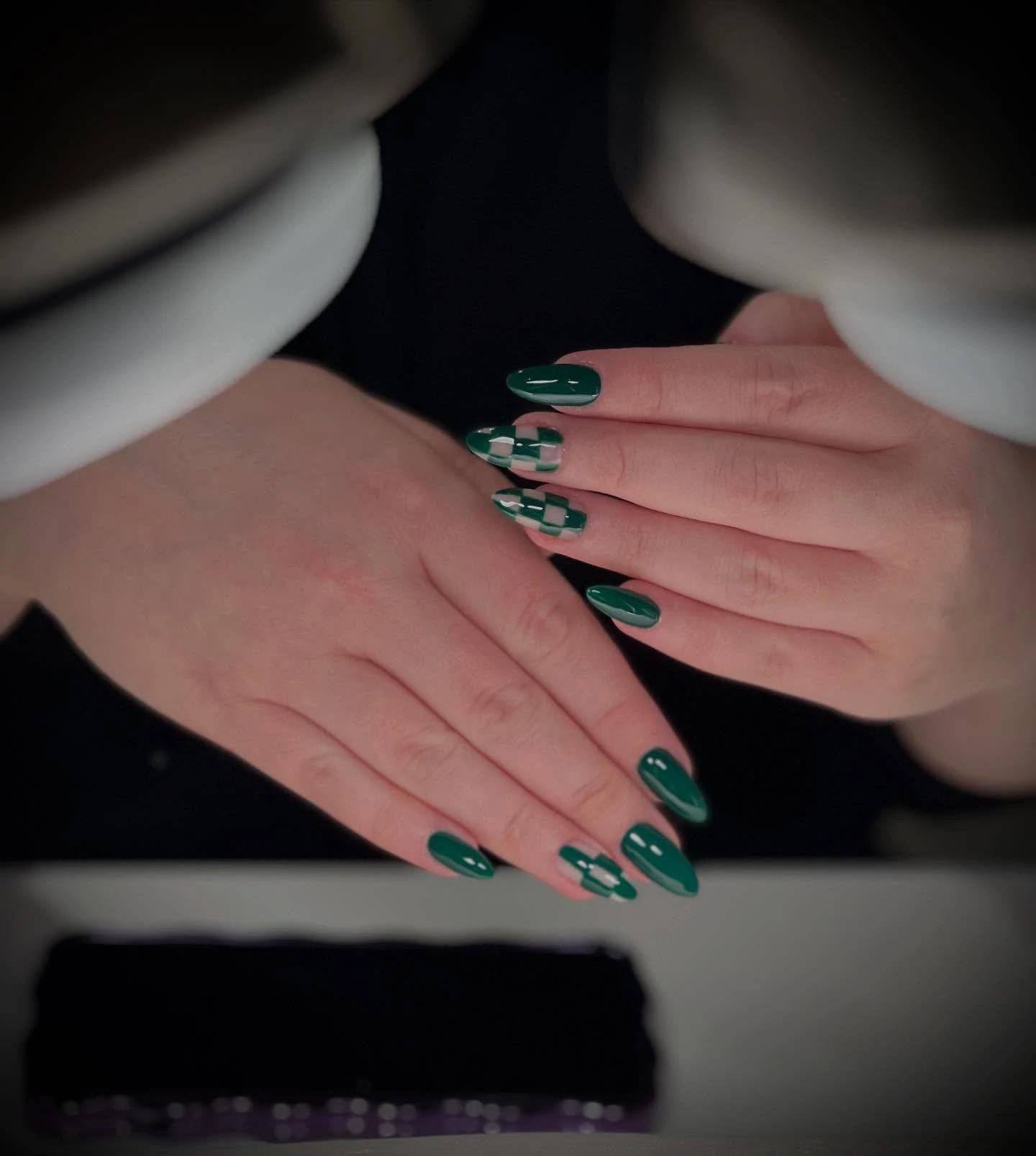 Deep emerald-green almond nails with checkerboard accent