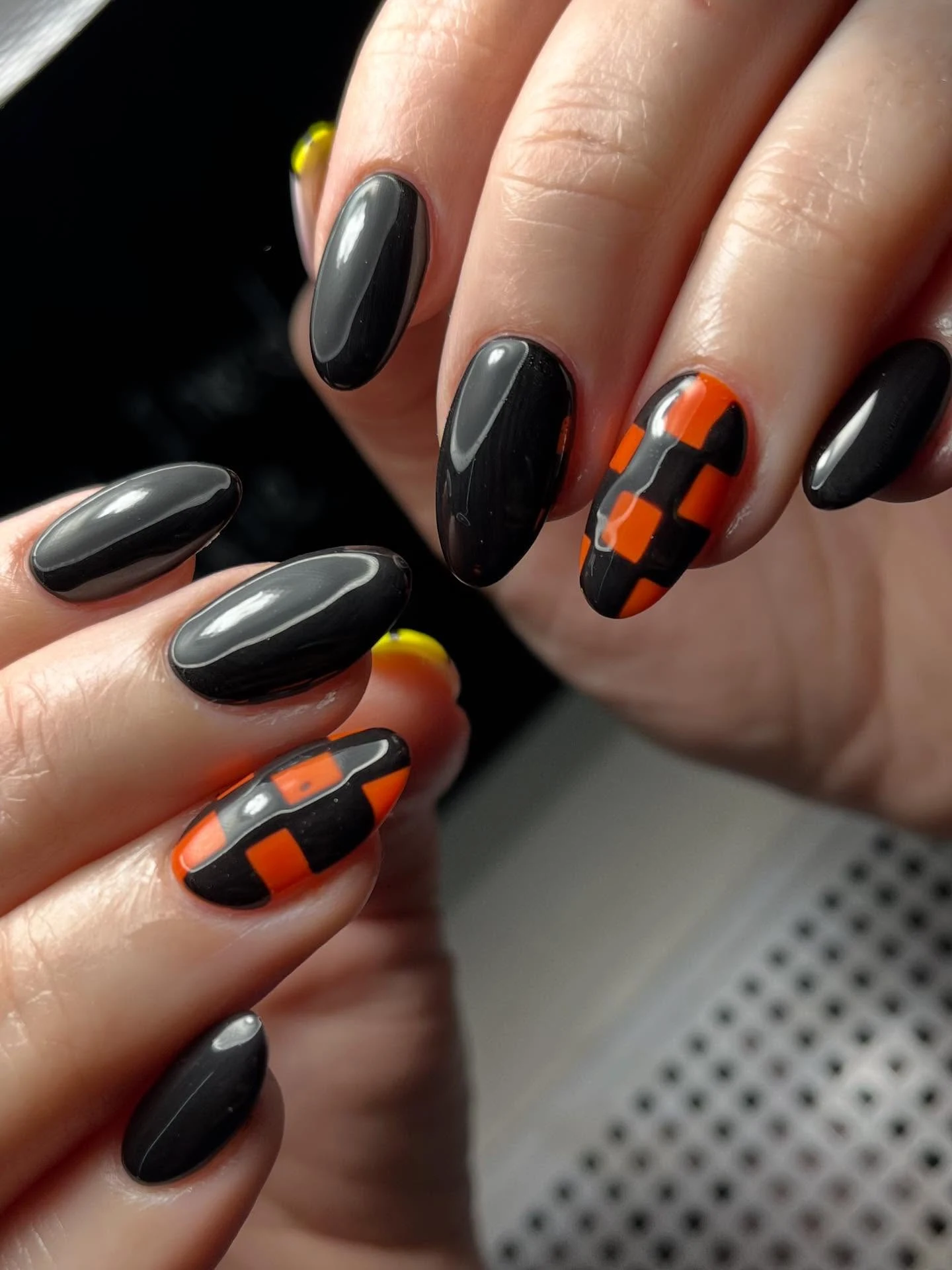 Black and grey nails with orange-checkerboard accent nails